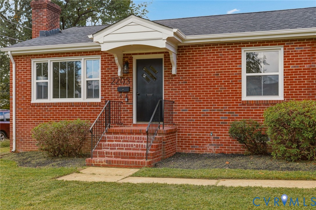 Red brick exterior with a black front door, white-framed windows, and a covered entry