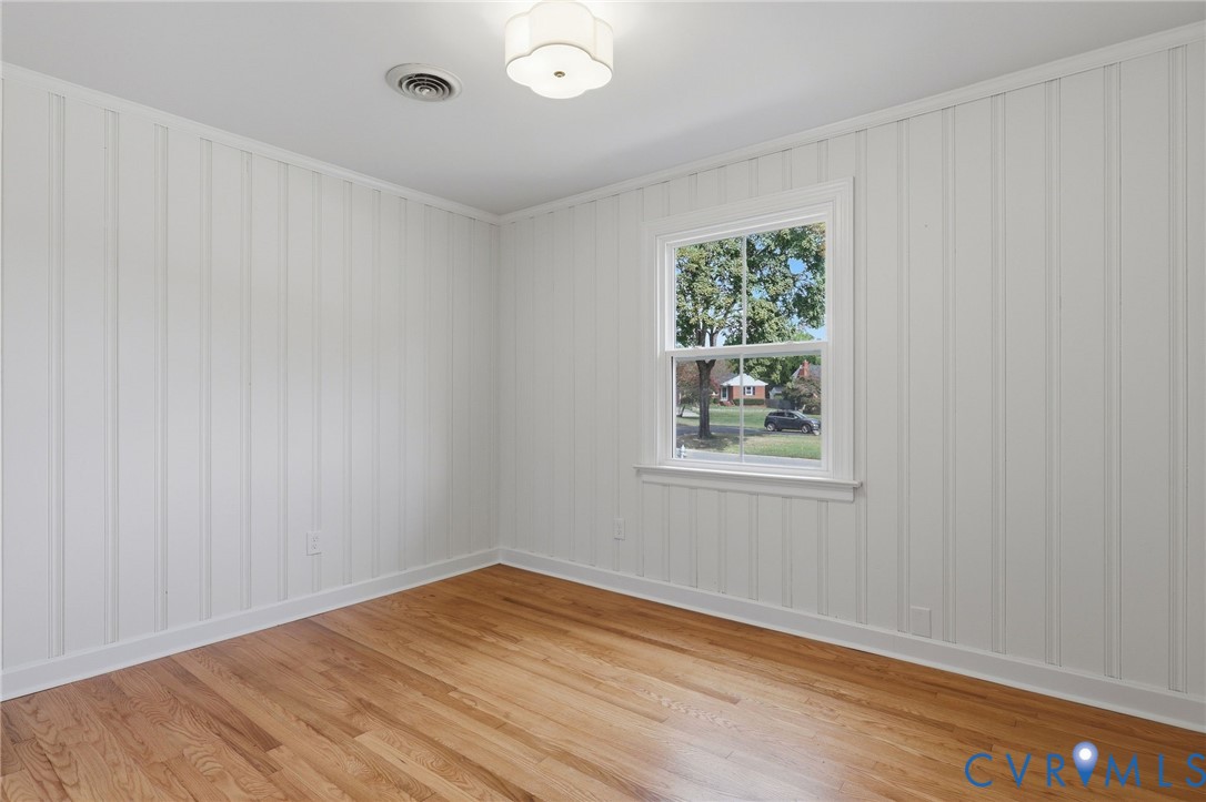 Hardwood flooring, white board-and-batten wall treatment, white trim, and a flush mount ceiling fixture