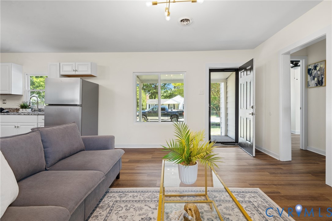 Open-concept living space featuring wood-finish flooring, white walls, and a contemporary ceiling fixture