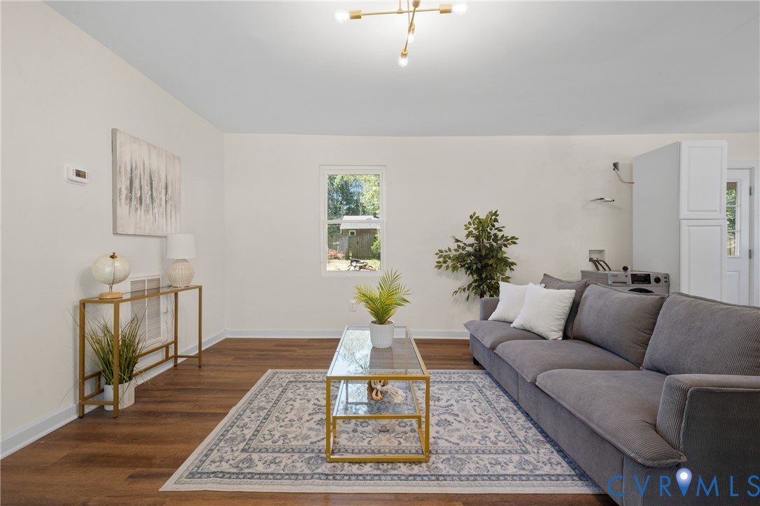 Spacious room featuring wood-finish flooring, a contemporary ceiling light fixture, and a single window