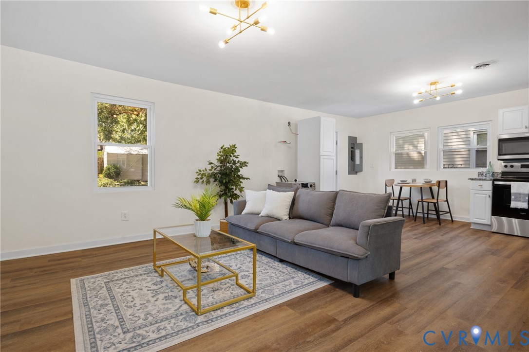 Open-concept living area featuring wood-finish flooring, white walls, and contemporary ceiling light fixtures