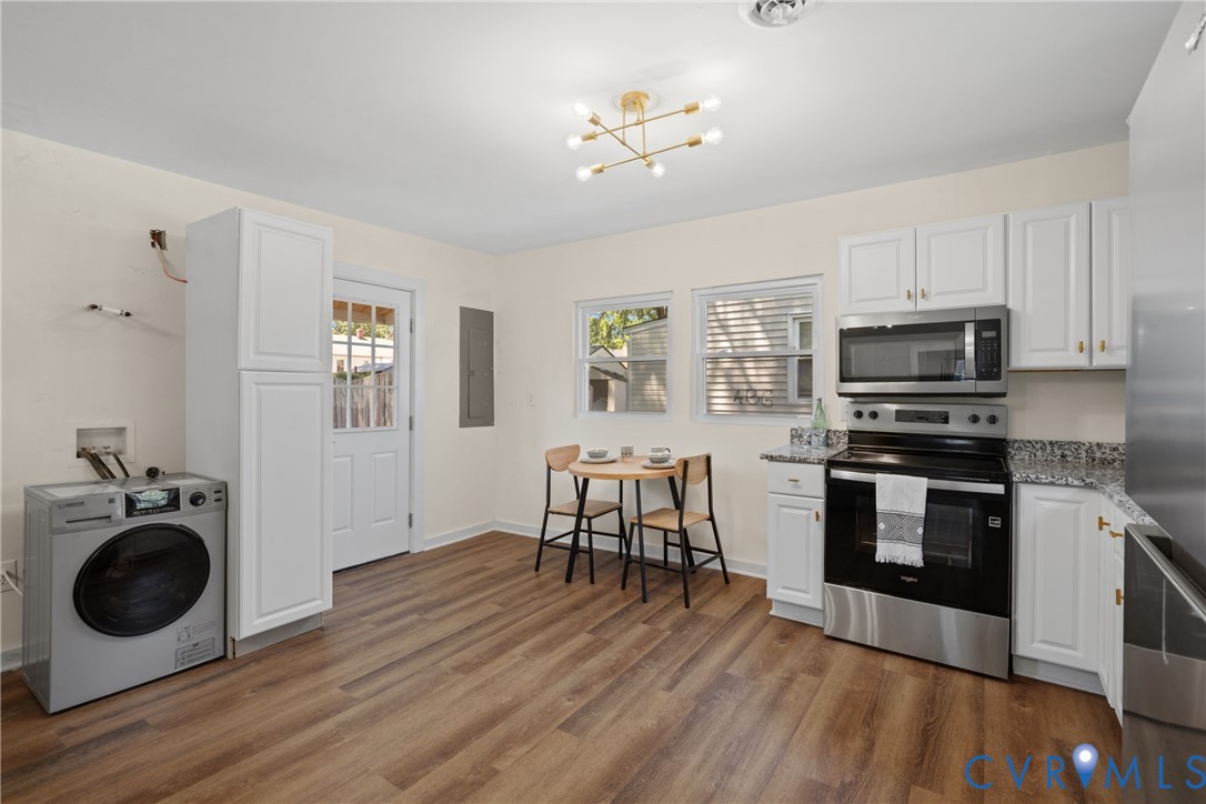 White cabinetry, stainless steel appliances, wood-finish flooring, and a modern ceiling light fixture