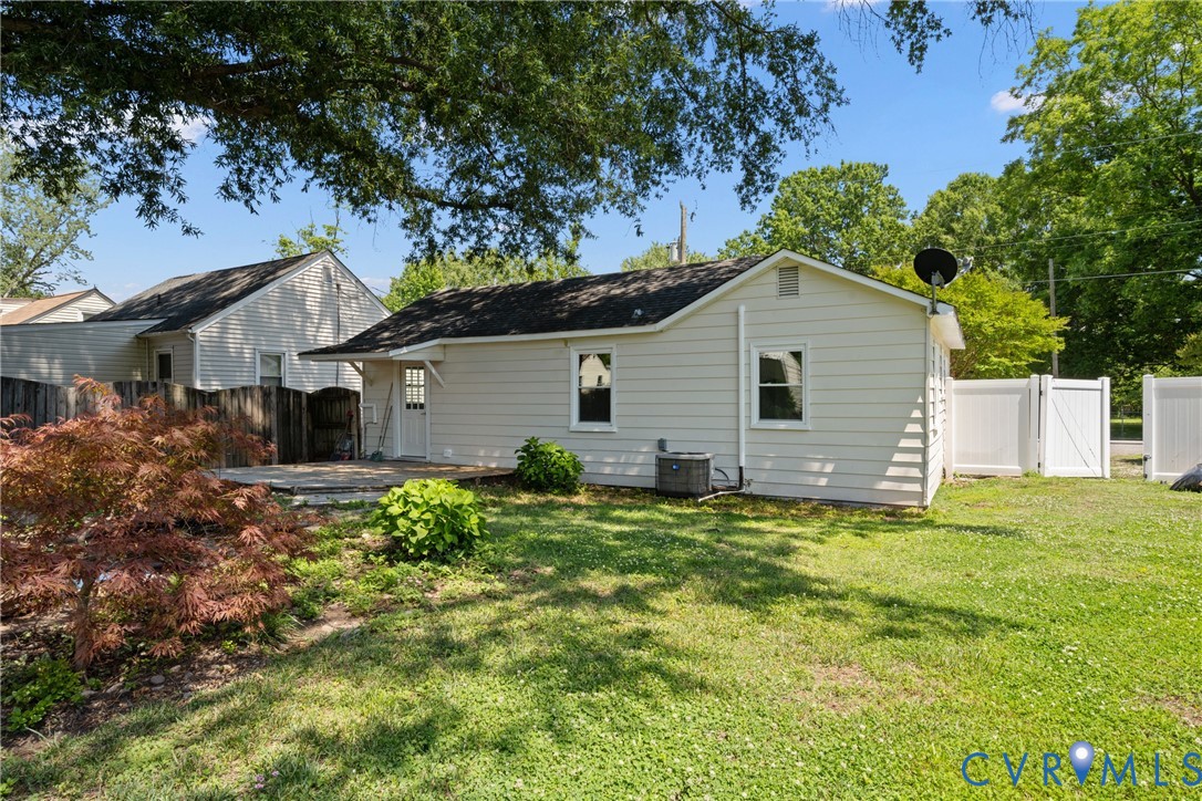 Expansive backyard featuring a manicured lawn, established landscaping, and a patio area