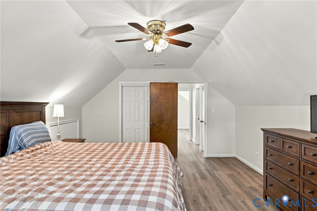 Vaulted ceilings with a multi-blade ceiling fan, wood-finish flooring, and multi-panel solid wood doors