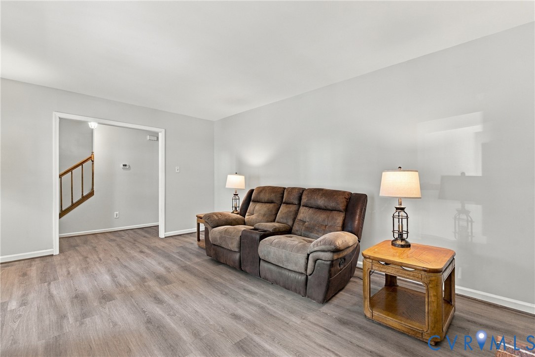 Neutral-toned walls paired with wood-finish flooring and a staircase featuring a traditional wooden banister