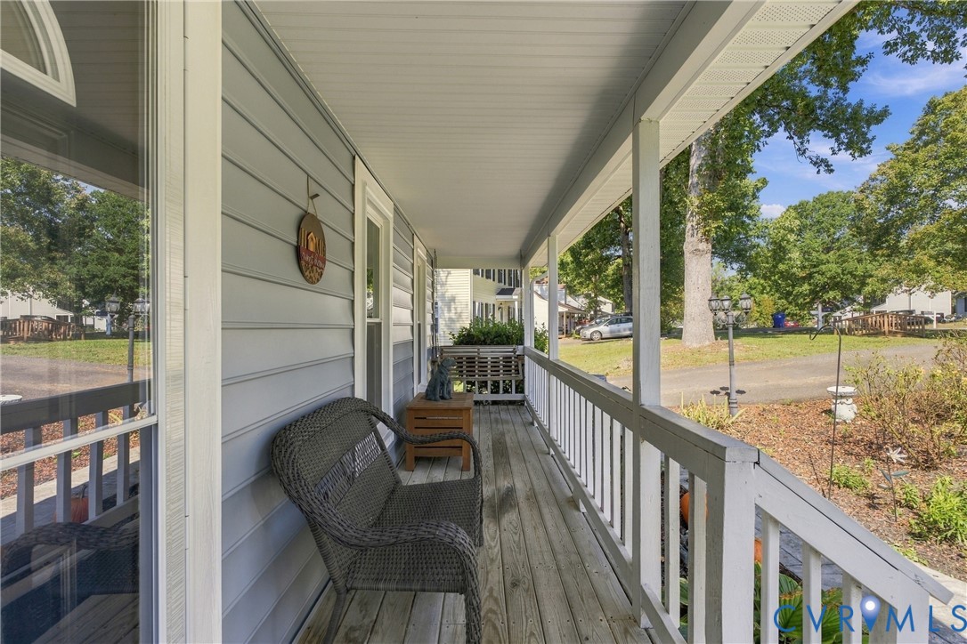 Covered front porch featuring wood-plank decking, white railings, and horizontal siding