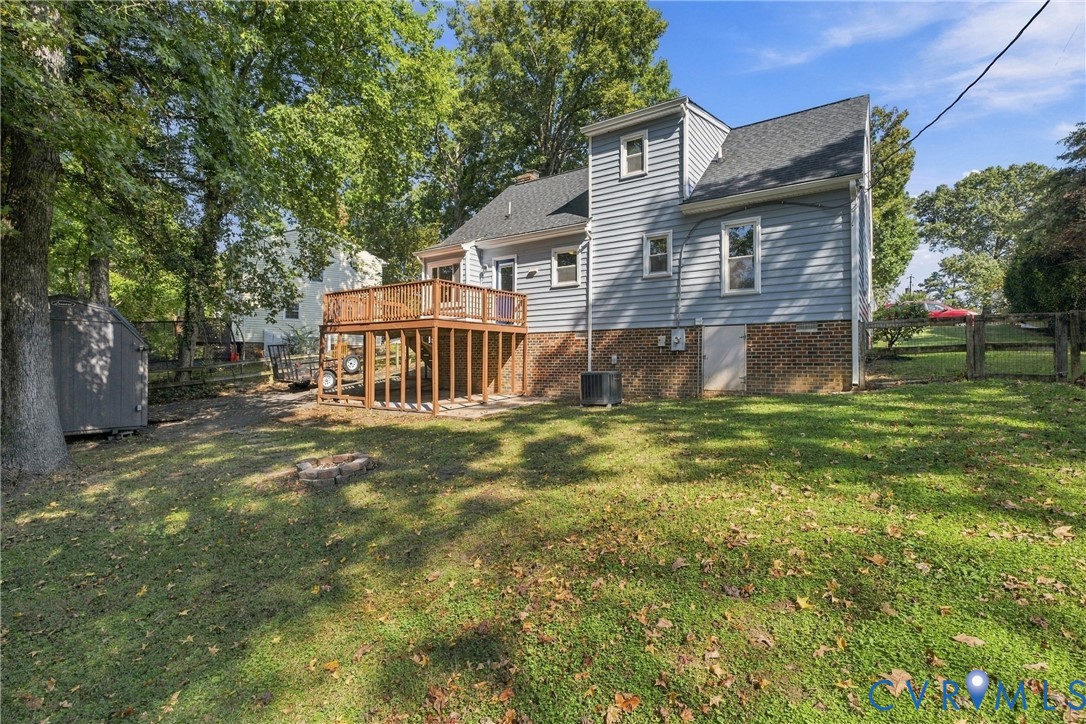 Two-story residence featuring light blue horizontal siding, a brick foundation, an elevated wooden deck, and a grass-covered backyard
