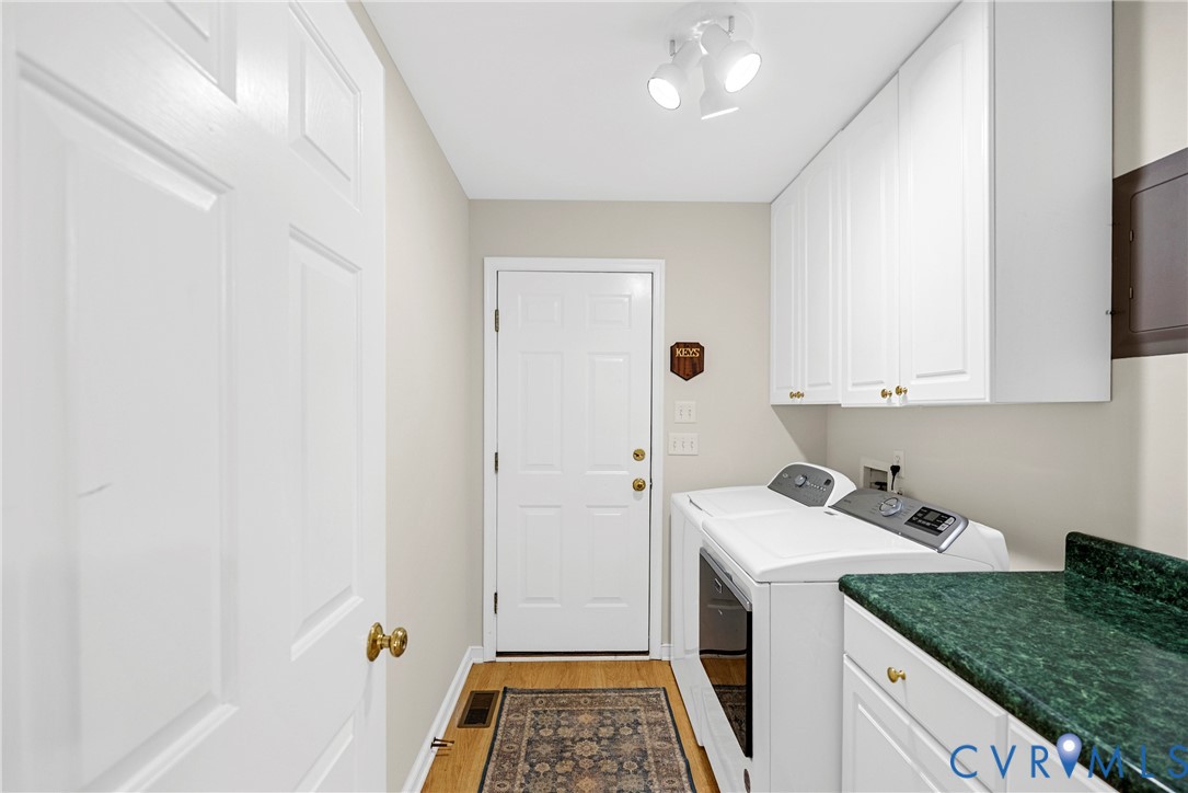 Laundry area featuring white shaker-style wall cabinets, a stone-finish countertop, wood-finish flooring, and multi-bulb track lighting