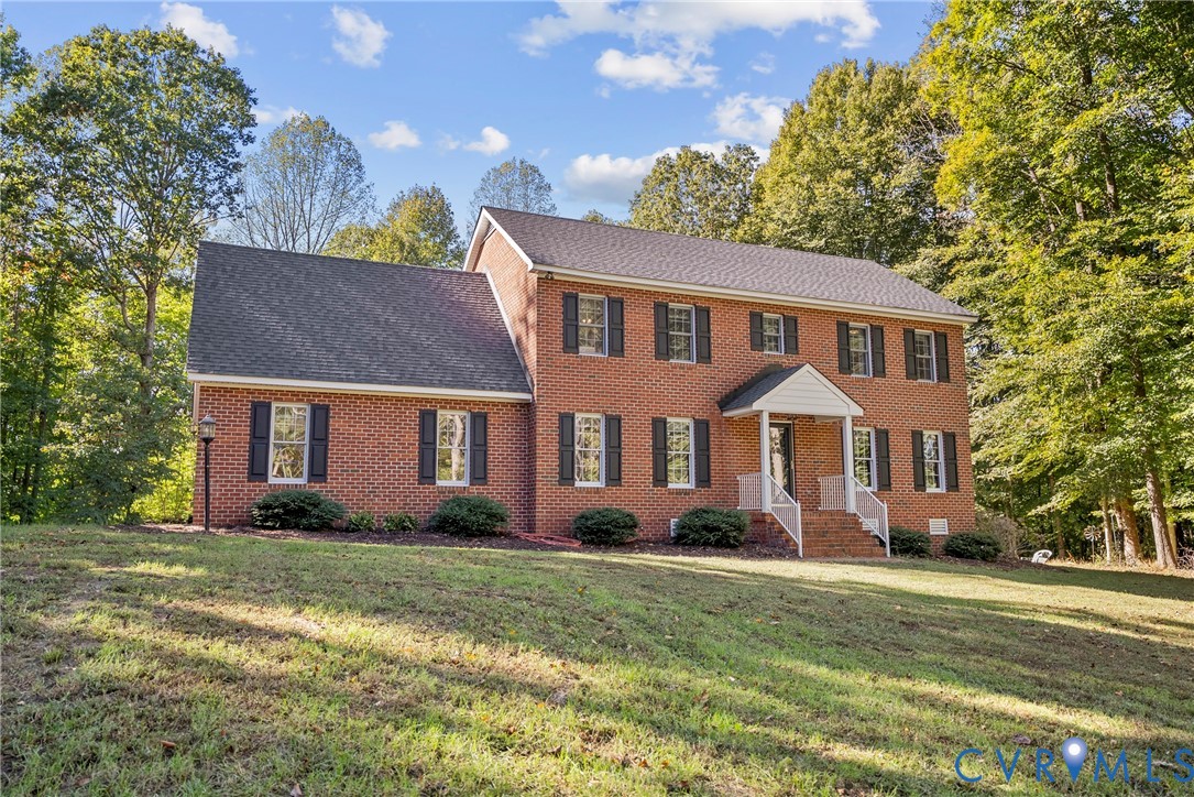 Two-story brick exterior featuring a gable-roofed front entry portico, white railings, and symmetrically placed dark shutters Two-story brick exterior featuring a gable-roofed front entry portico, white railings, and symmetrically placed dark shutters
