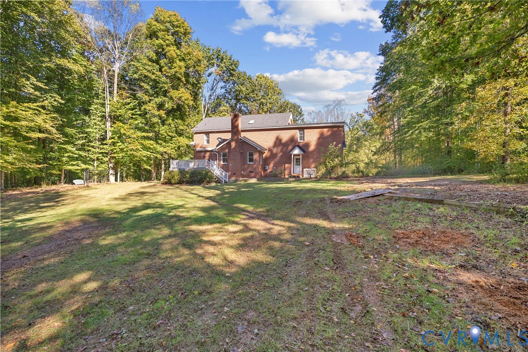 Brick exterior residence featuring a rear elevated deck and surrounding wooded acreage