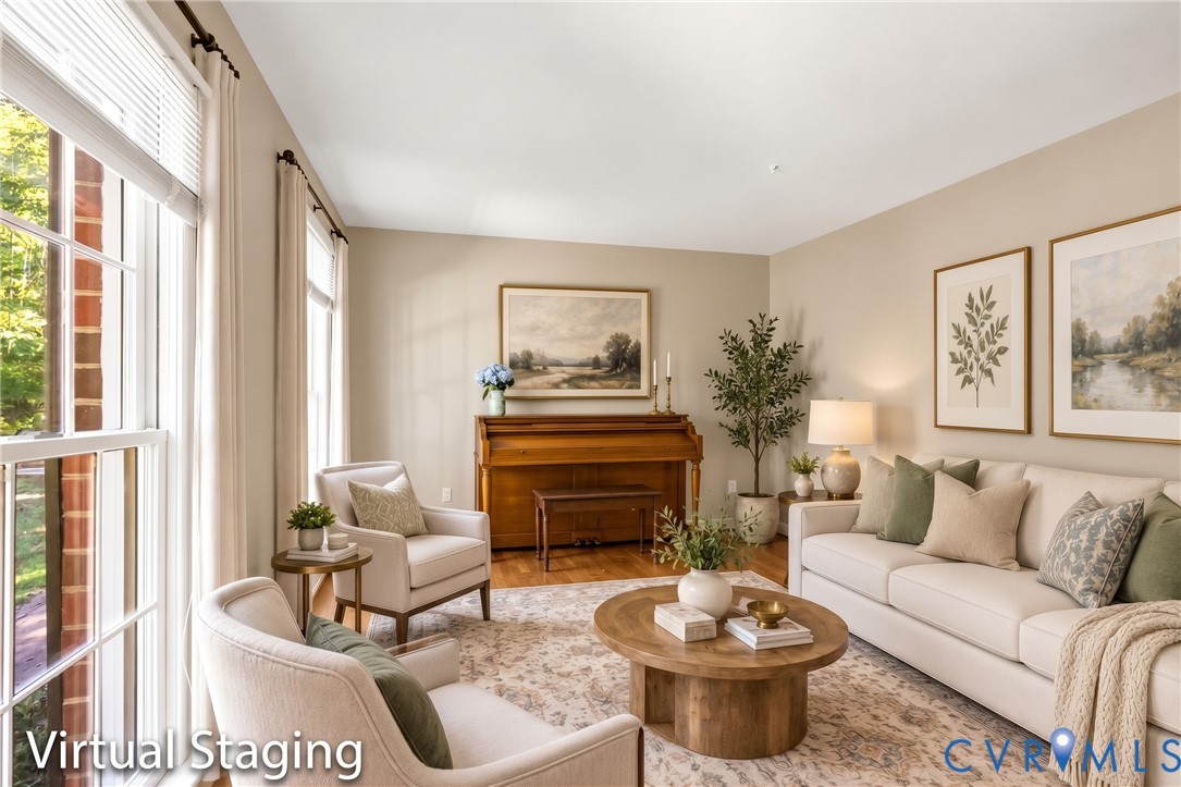 Living area featuring wood-finish flooring, tall multi-pane windows, and a brick-accented wall section