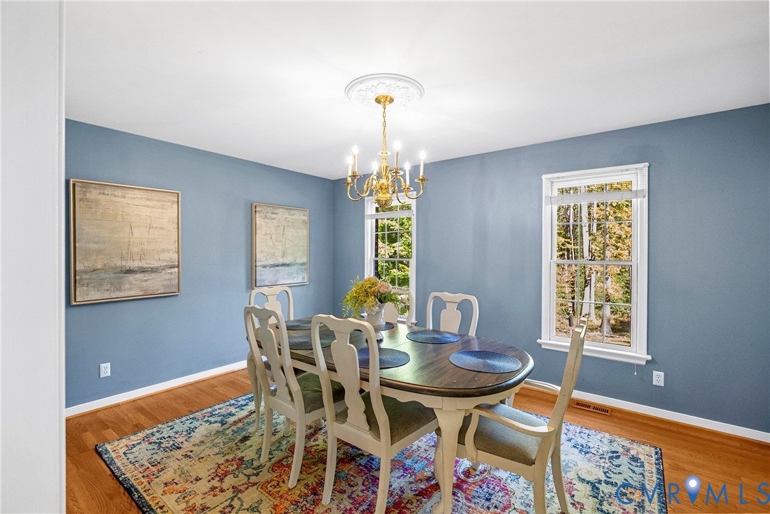 Dining area featuring wood-finish flooring, two double-hung windows, and a decorative ceiling medallion with a classic multi-arm chandelier