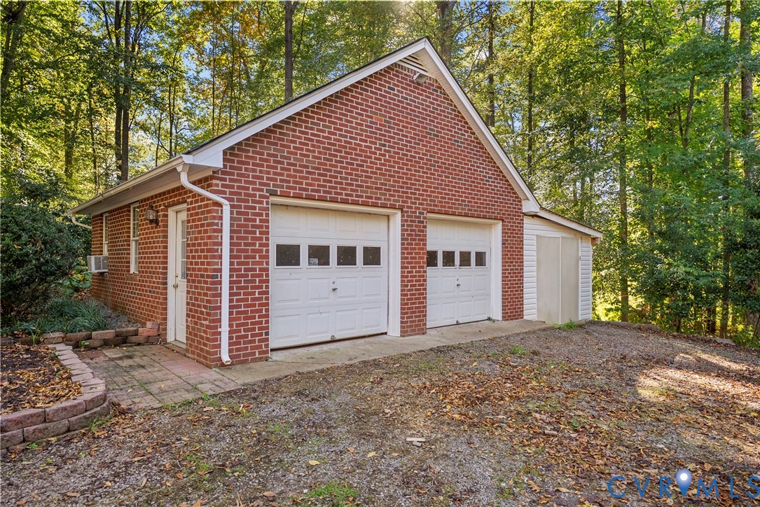 Detached brick garage featuring a dual-bay configuration, white sectional doors with windows, a side-entry pedestrian door, and a dedicated storage shed extension