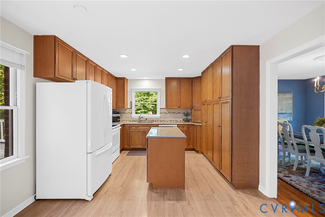 Kitchen featuring wood cabinetry, central island with stone countertop, recessed ceiling lighting, and wood-finish flooring