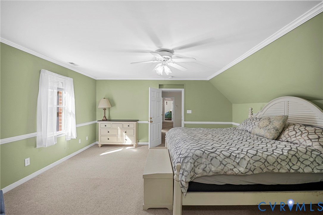 Room featuring vaulted ceilings, chair rail molding, wall-to-wall carpeting, and a central ceiling fan with integrated lighting