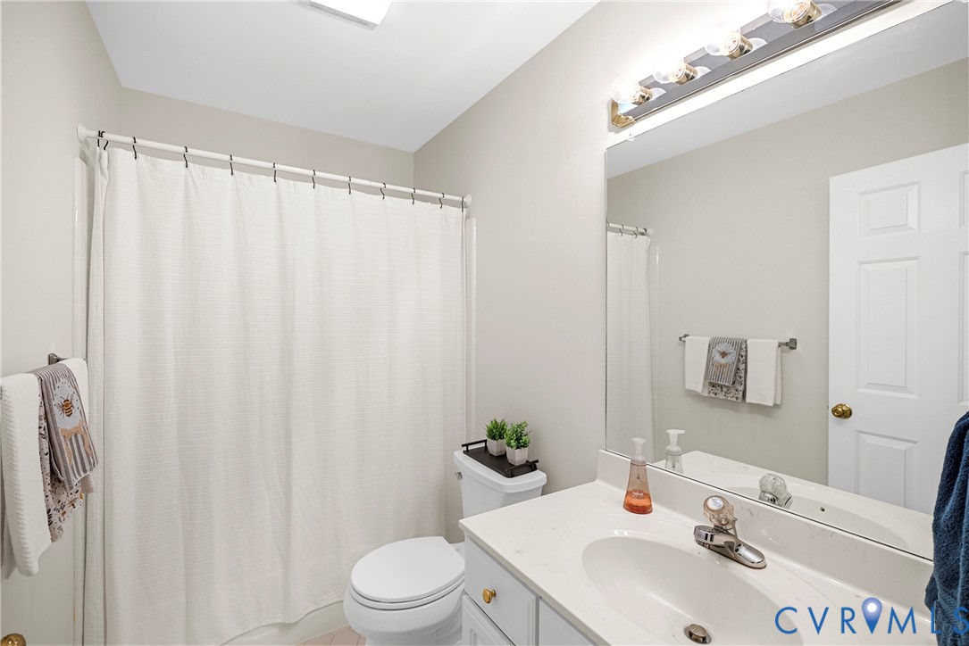 Bathroom featuring a vanity with a light-toned countertop, integrated basin, and brushed-nickel faucet, complemented by a large wall-mounted mirror and multi-bulb vanity lighting