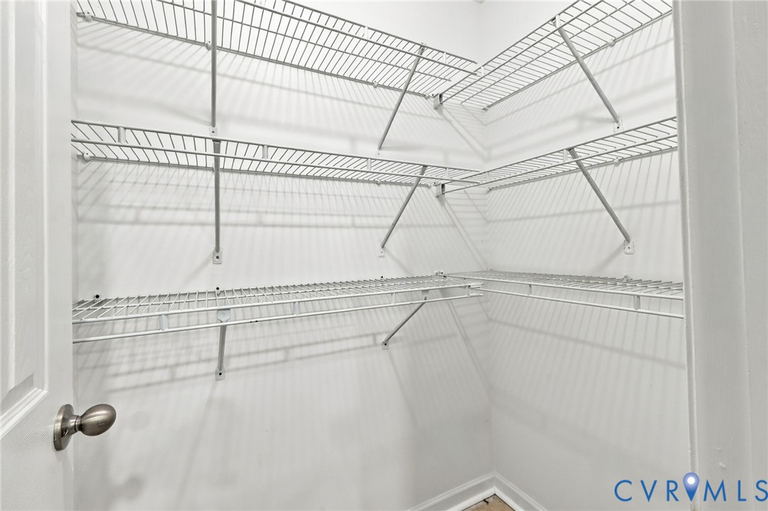 Walk-in storage space featuring tiered white wire shelving and a brushed metal door handle