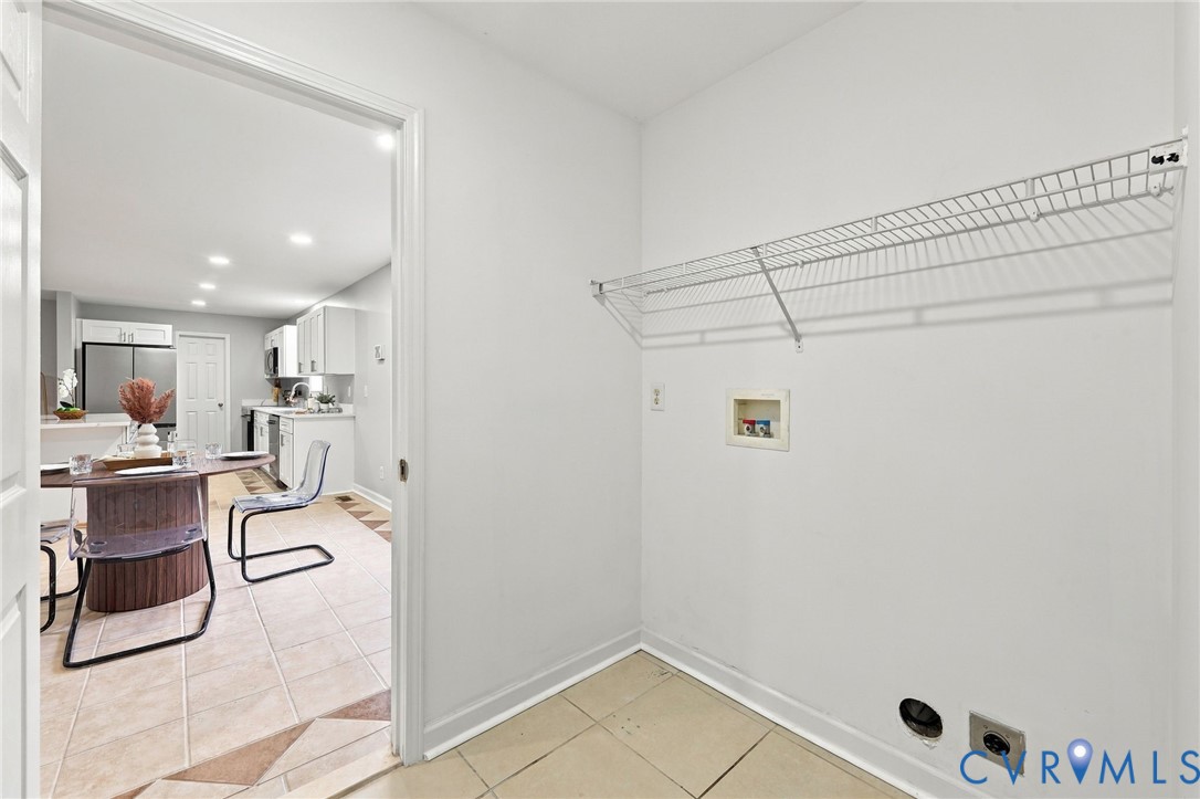 Utility space featuring tile flooring and a wall-mounted wire shelving unit