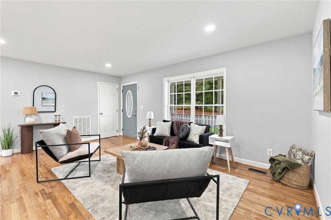 Living area featuring wood-finish flooring, recessed lighting, and a multi-pane window with a grid pattern Living area featuring wood-finish flooring, recessed lighting, and a multi-pane window with a grid pattern