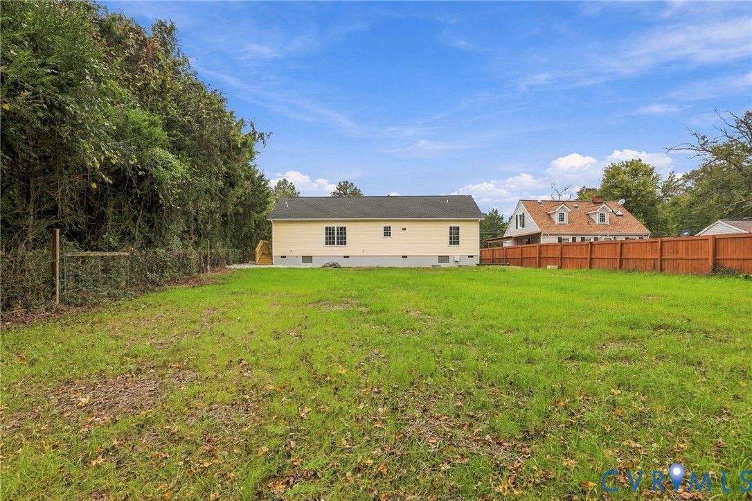 Expansive backyard featuring a level lawn, mature tree line, and full-perimeter wood fencing