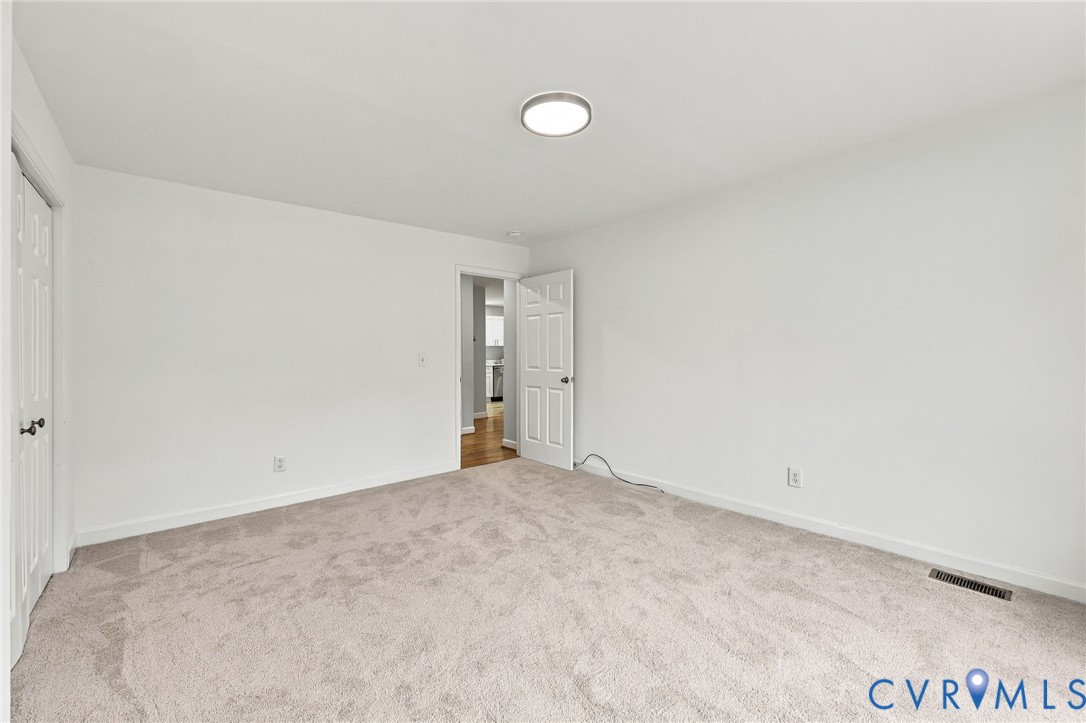 Neutral interior space featuring wall-to-wall carpeting, white walls, six-panel interior doors, and a flush-mount circular ceiling fixture