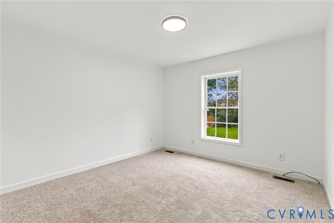 Neutral wall-to-wall carpeting, crisp white wall finishes, single-pane window with grid detailing, and recessed circular ceiling lighting