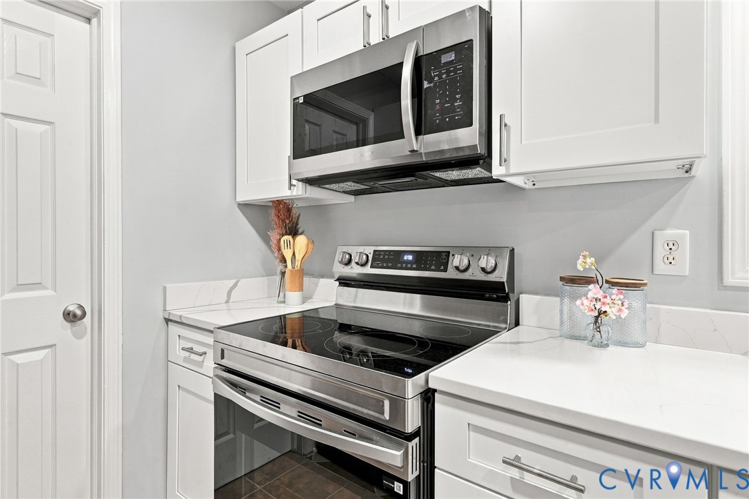 Kitchen featuring white shaker-style cabinetry, quartz countertops with veining, stainless steel electric range, and stainless steel built-in microwave