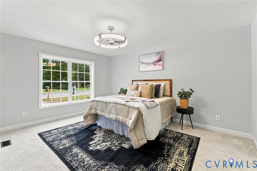 Room interior featuring wall-to-wall carpeting, a large grid-pane window, and a modern circular LED ceiling fixture