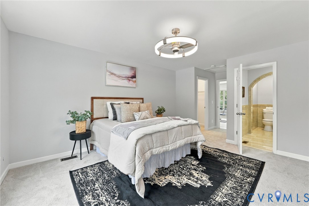Neutral-toned room featuring a contemporary ceiling fan with integrated circular lighting and tile flooring within the attached bathroom accented by an arched doorway