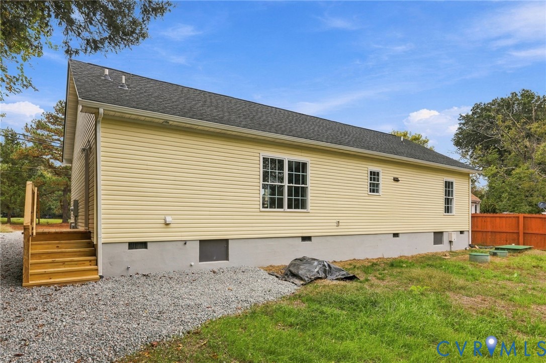 Exterior featuring yellow vinyl siding, a gabled roof, a concrete foundation, and wooden staircase access