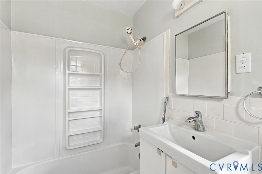Full bathroom featuring a tub/shower combination, white vanity with integrated sink, and an integrated medicine cabinet Full bathroom featuring a tub/shower combination, white vanity with integrated sink, and an integrated medicine cabinet