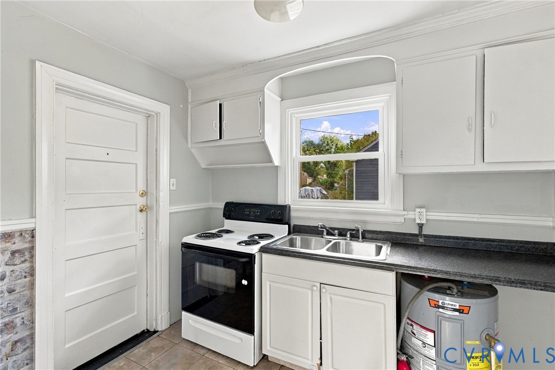 Kitchen with a white paneled door, gray painted walls, and tile flooring