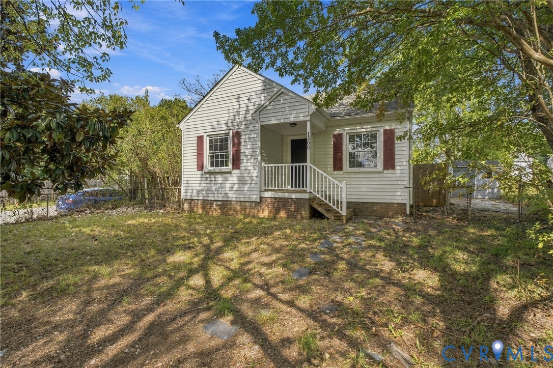 White siding exterior with a covered front porch, red window shutters, and a sloped roofline