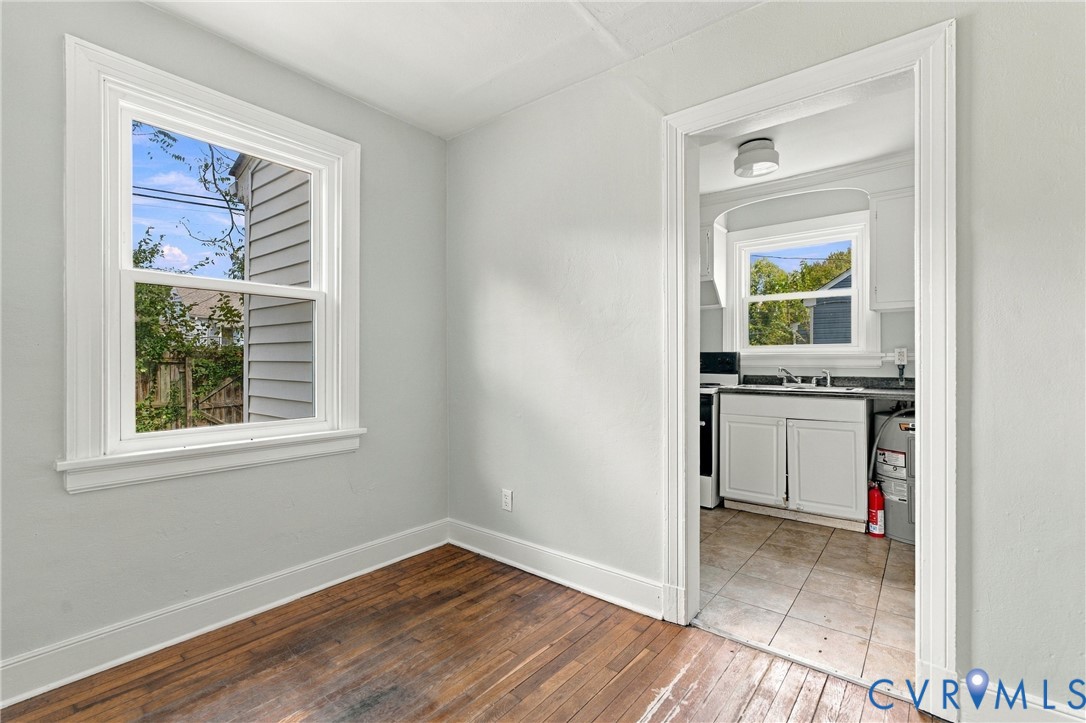 Hardwood flooring, painted interior walls, white trim, white window, and an arched doorway