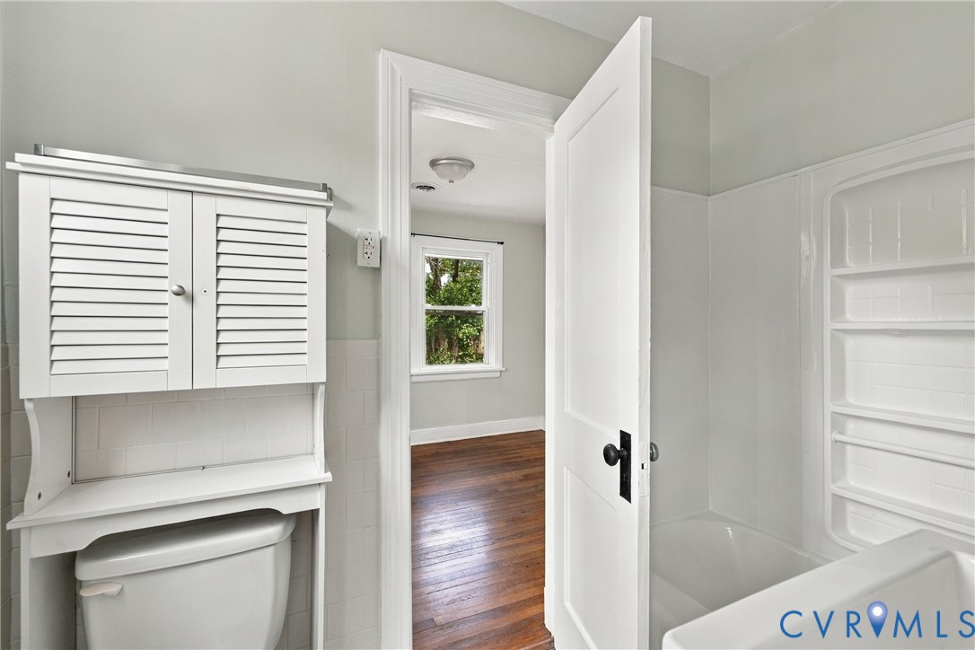 White louvered cabinet, white tiled bathtub surround, and a white interior door with black hardware White louvered cabinet, white tiled bathtub surround, and a white interior door with black hardware