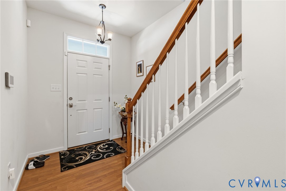 Entryway featuring wood-finish flooring, a white paneled door with transom window, and a chandelier