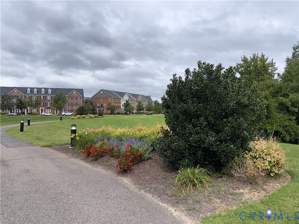 Landscaped grounds featuring a paved pathway, decorative bollard lighting, and a variety of mature shrubs and colorful plantings