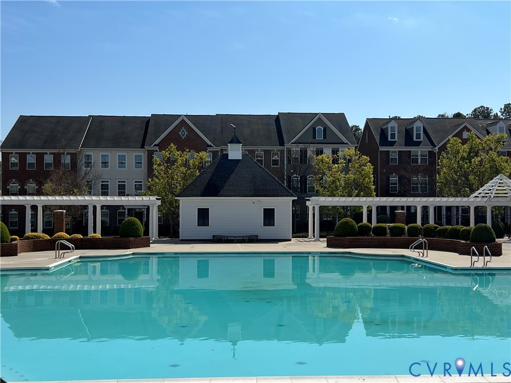 Outdoor swimming pool with integrated steps, surrounding pergola structures, and a white cabana building