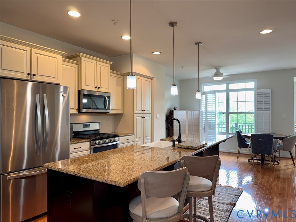 Kitchen featuring a large central island with granite countertop, stainless steel appliances, recessed lighting, and wood-finish flooring