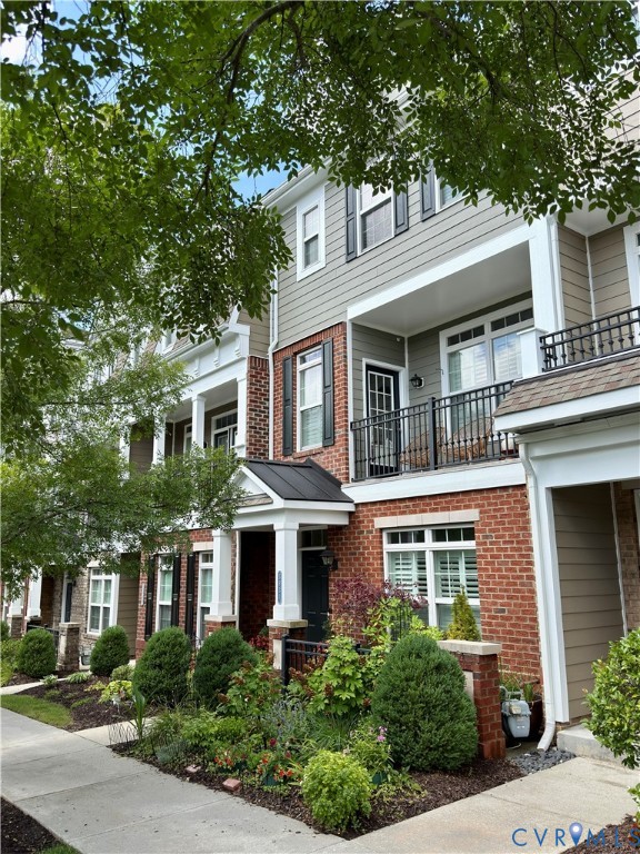 Townhome exterior featuring a brick facade, gray siding, and black window shutters Townhome exterior featuring a brick facade, gray siding, and black window shutters