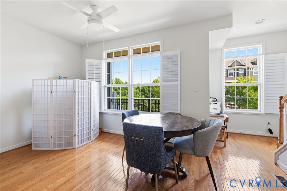 Hardwood flooring, plantation shutters, white ceiling fan, and multiple windows