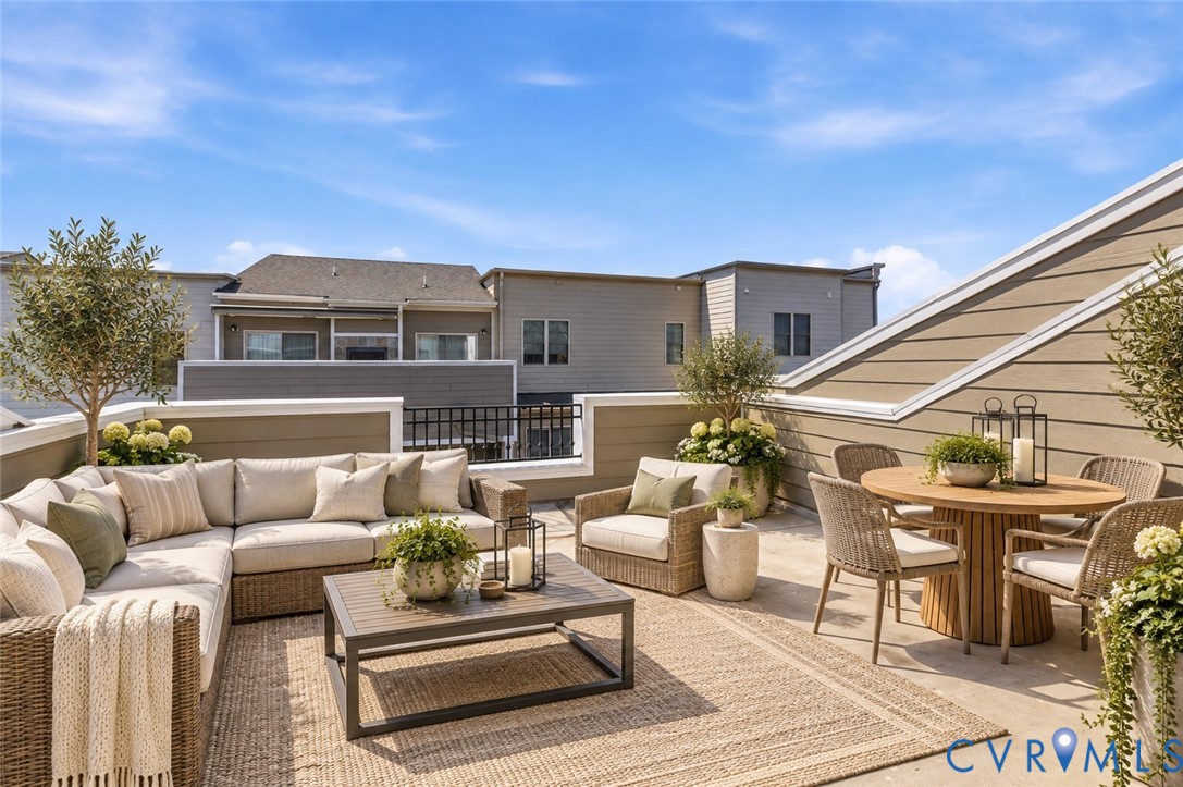Expansive rooftop patio featuring a sloped exterior wall, perimeter railing, and ample space for outdoor living
