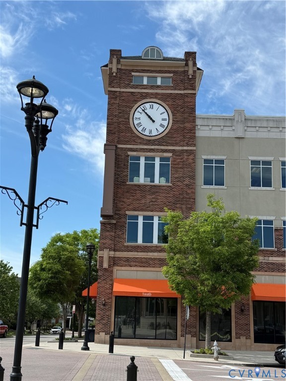 Brick faade clock tower building with multiple windows, street lamps, and sidewalk paving