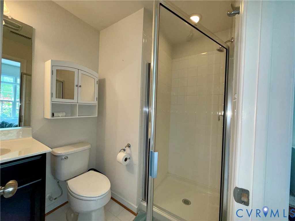 Bathroom featuring a glass-enclosed shower, white tiled shower surround, recessed shower lighting, and a wall-mounted medicine cabinet with mirrored doors