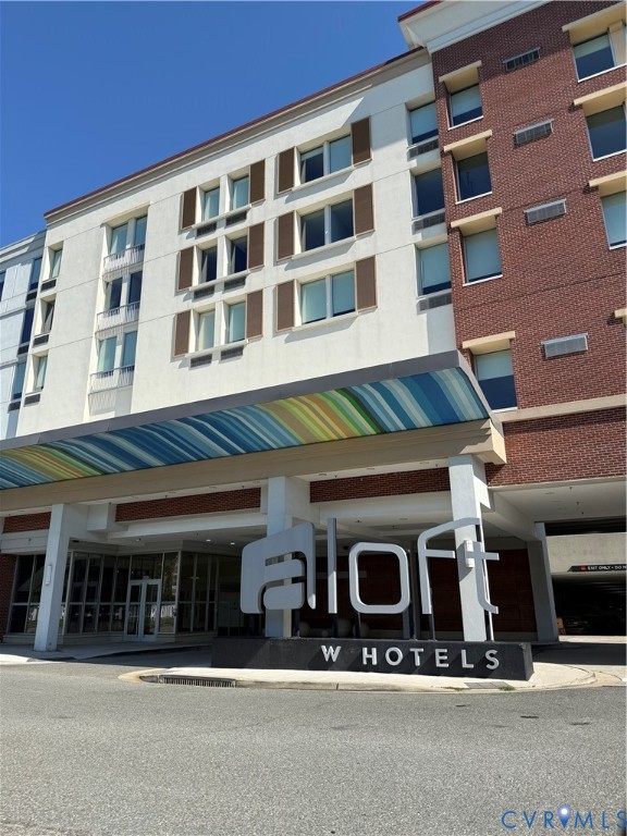 Multi-story commercial building featuring a white facade with brown shutters, a brick facade, and a prominent brand signage