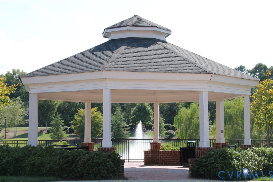 Octagonal gazebo with a shingled roof, white columns, and brick bases