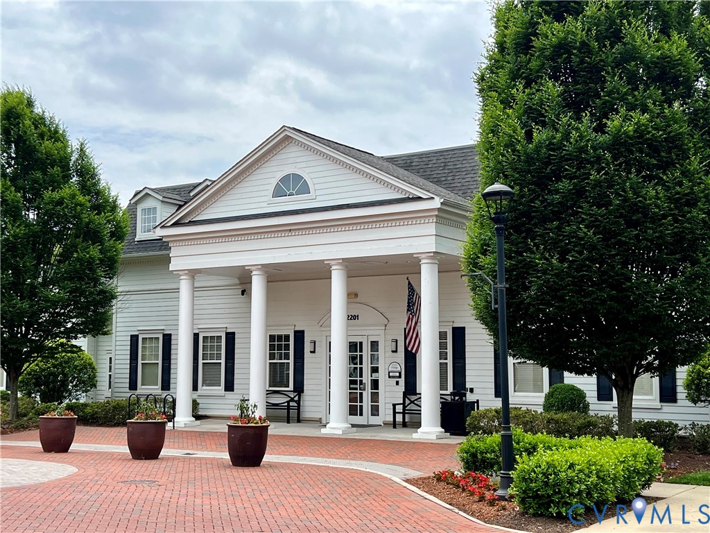 White exterior with dark shutters, prominent columns, dormer window, and a gabled roof