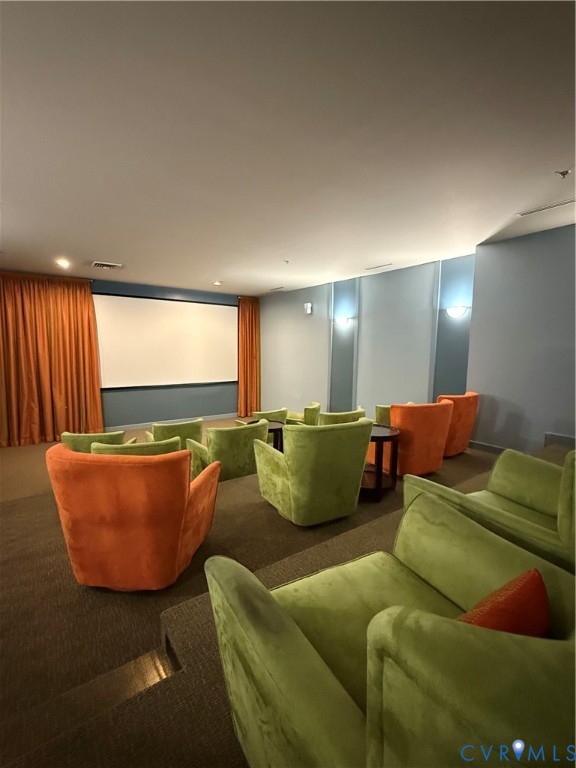 Tiered seating with plush upholstered chairs, projection screen, and wall sconce lighting