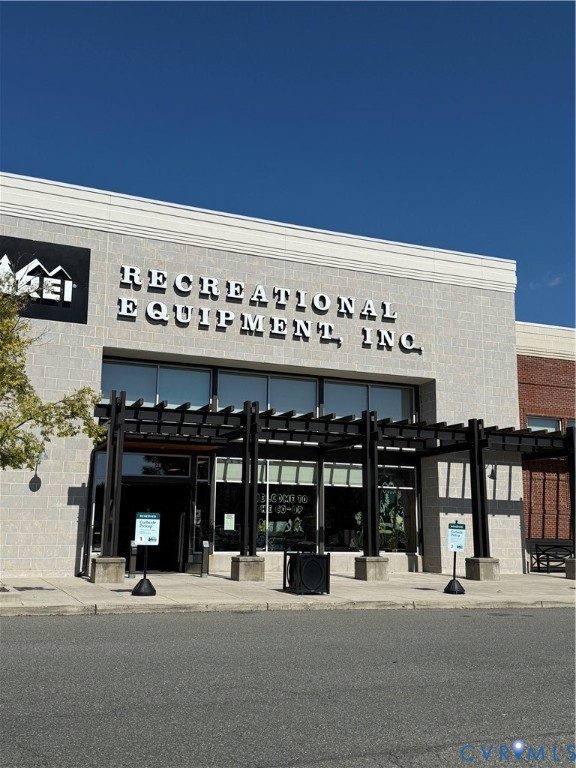 Stone facade with large storefront windows and a dark-toned pergola entry