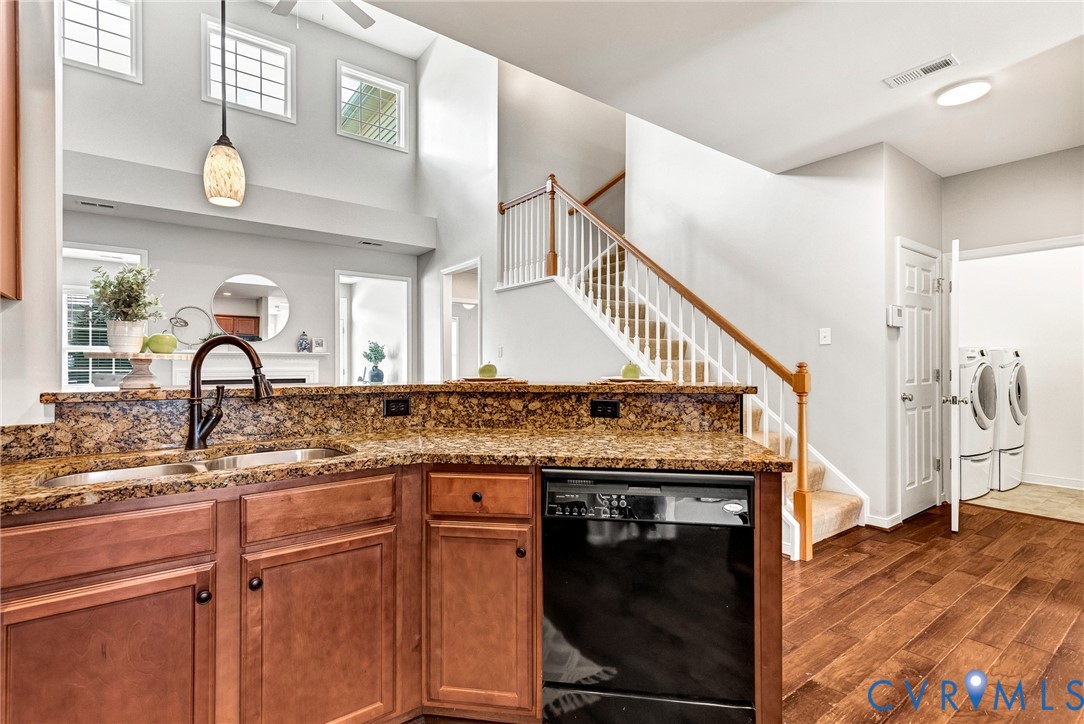 Kitchen featuring a double basin sink with a gooseneck faucet, integrated dishwasher, and wood cabinetry